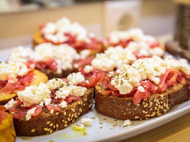 Mehrere Scheiben Brot mit Feta-Käse und Tomaten auf einem Tablett im Pyrgaki Hotel.