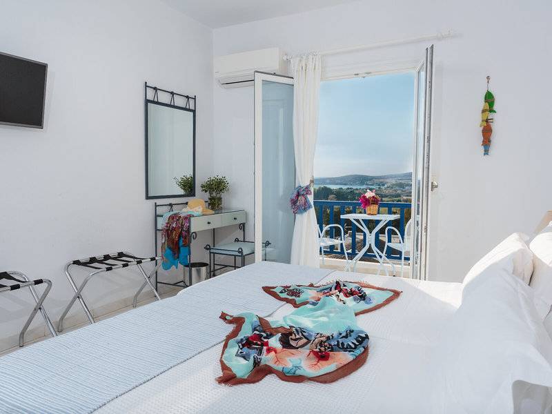 Schlafzimmer mit Balkon im Pyrgaki Hotel, mit Bett, Klimaanlage, Fernseher und Blick auf die Landschaft.