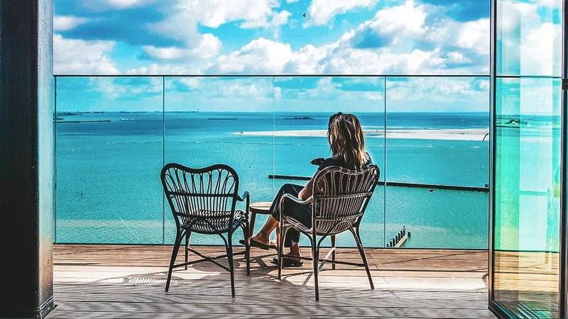 Frau auf dem Balkon des Four Elements Hotel Amsterdam mit Blick auf das Meer