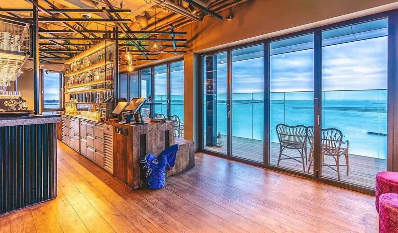 Innenansicht der Bar im Four Elements Hotel Amsterdam mit Blick auf das Meer.