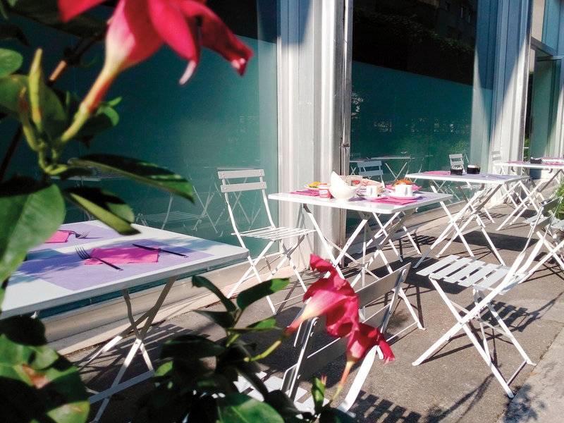 Terrasse des Ripa Roma Hotels mit mehreren weißen Tischen und Stühlen draußen.