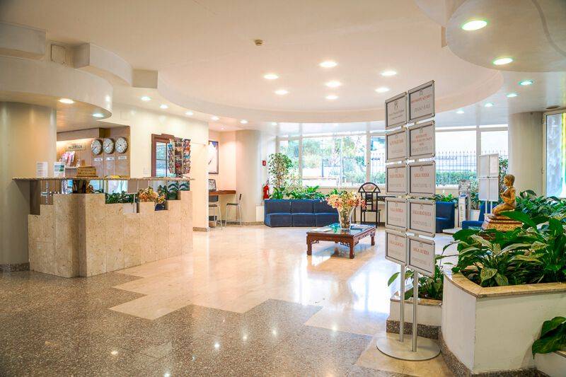 Empfangsbereich des Pineta Palace Hotels mit Rezeptionstresen, Sofas, Pflanzen und Dekor.