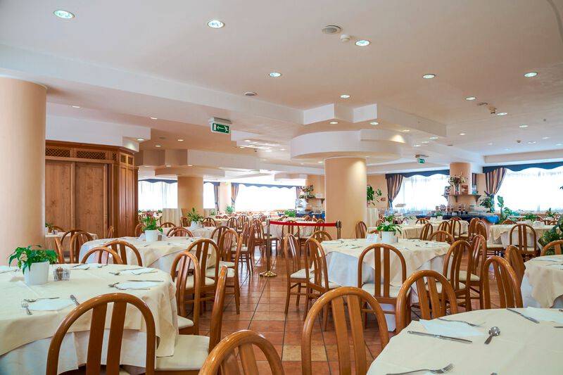 Innenansicht des Restaurants im Pineta Palace Hotel mit gedeckten Tischen und Stühlen.
