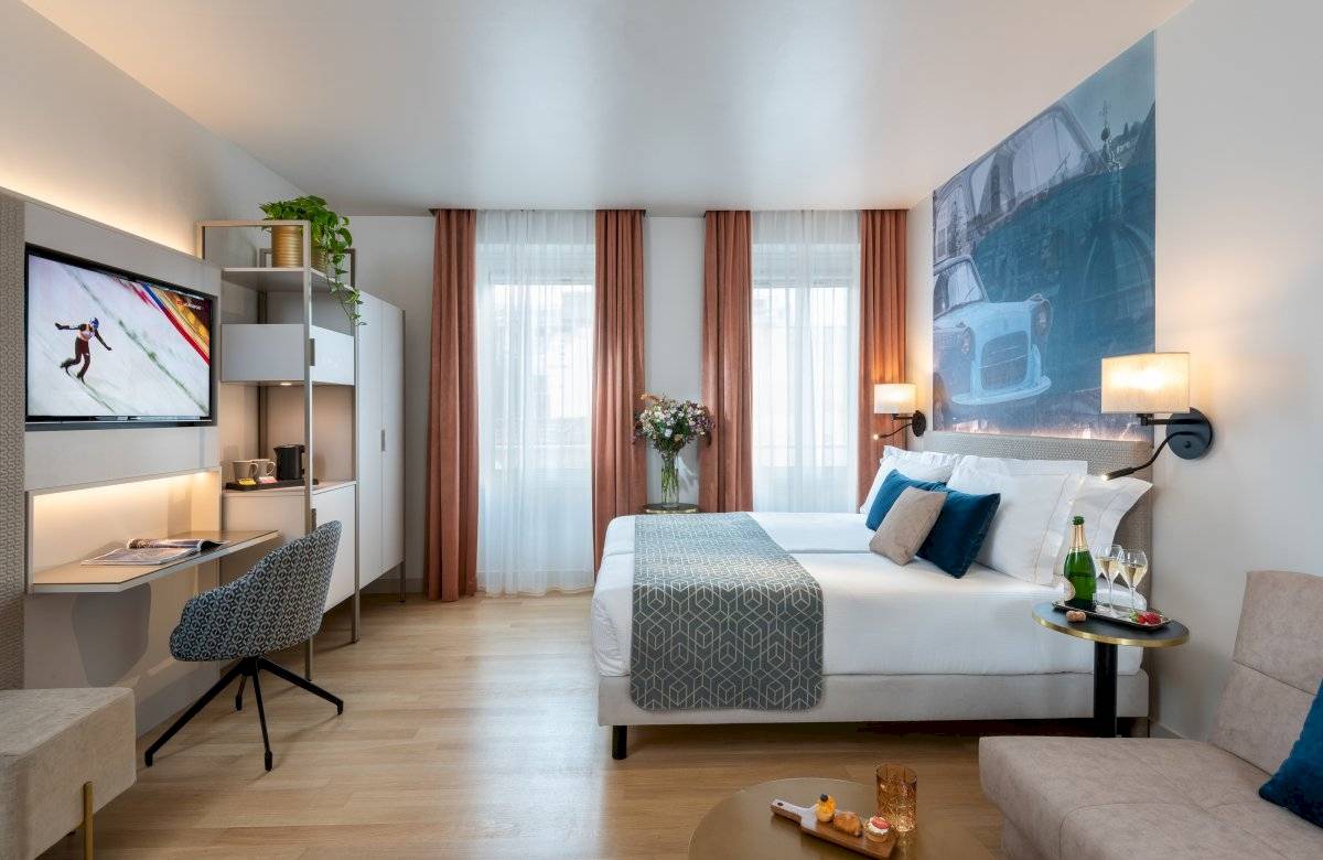 Leonardo Boutique Hotel Rome Termini Zimmer mit Bett, Schreibtisch, Fernseher und Blumen.