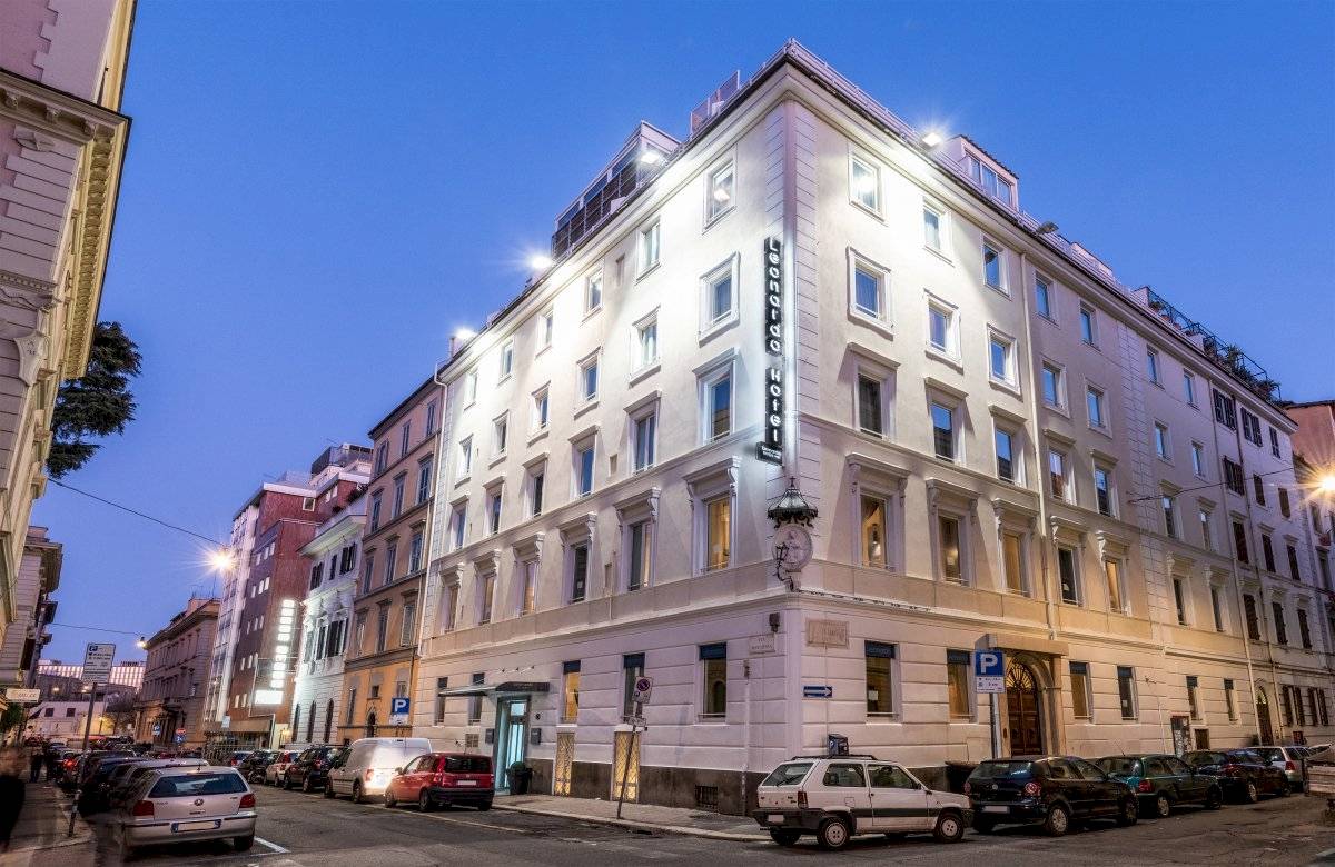 Leonardo Boutique Hotel Rome Termini Außenansicht bei Nacht mit Beleuchtung und parkenden Autos.