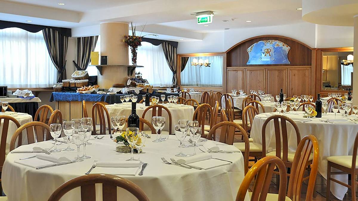 Speisesaal im Pineta Palace Hotel mit gedeckten Tischen, Flaschen und Gläsern.