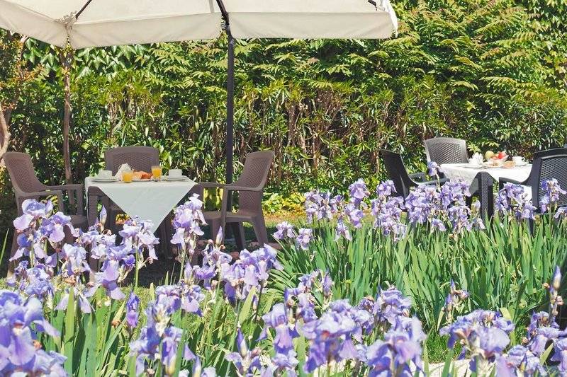 Frühstückstisch im Garten des Tre Archi Hotels mit Irisblumen im Vordergrund