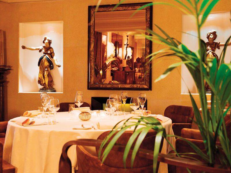 Metropole Hotel Restaurant mit gedecktem Tisch und Stühlen vor einem Spiegel.