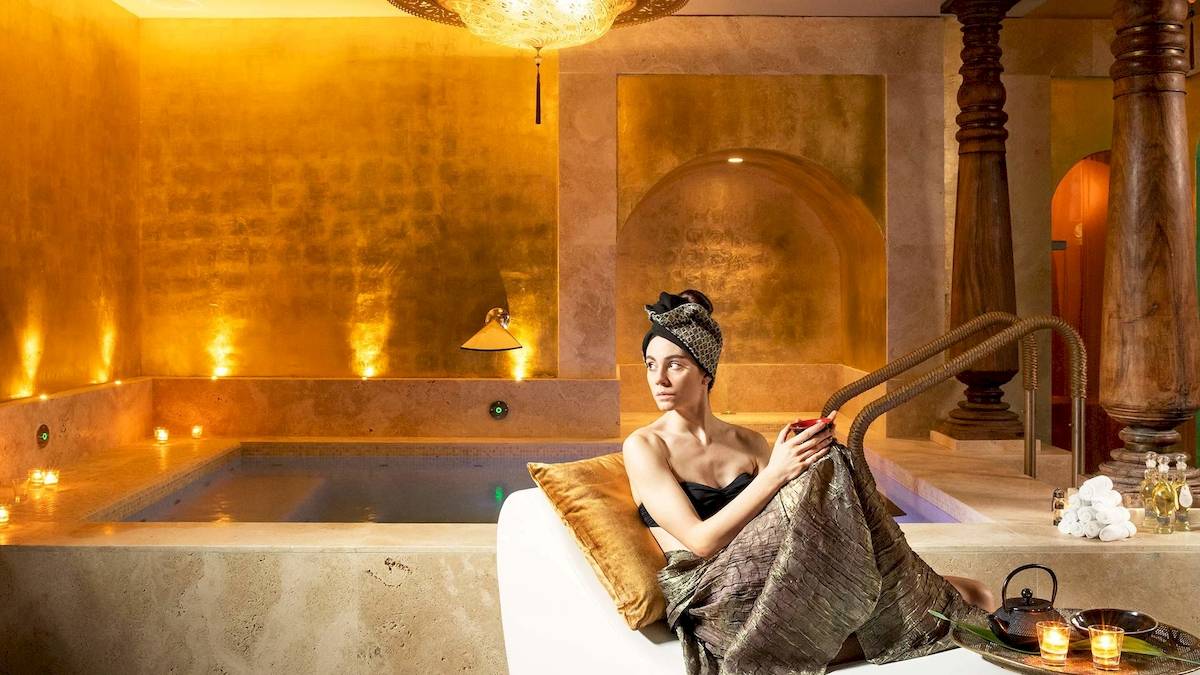 Eine Frau sitzt im Liegestuhl im Spa-Bereich des Metropole Hotels, neben einem Whirlpool.