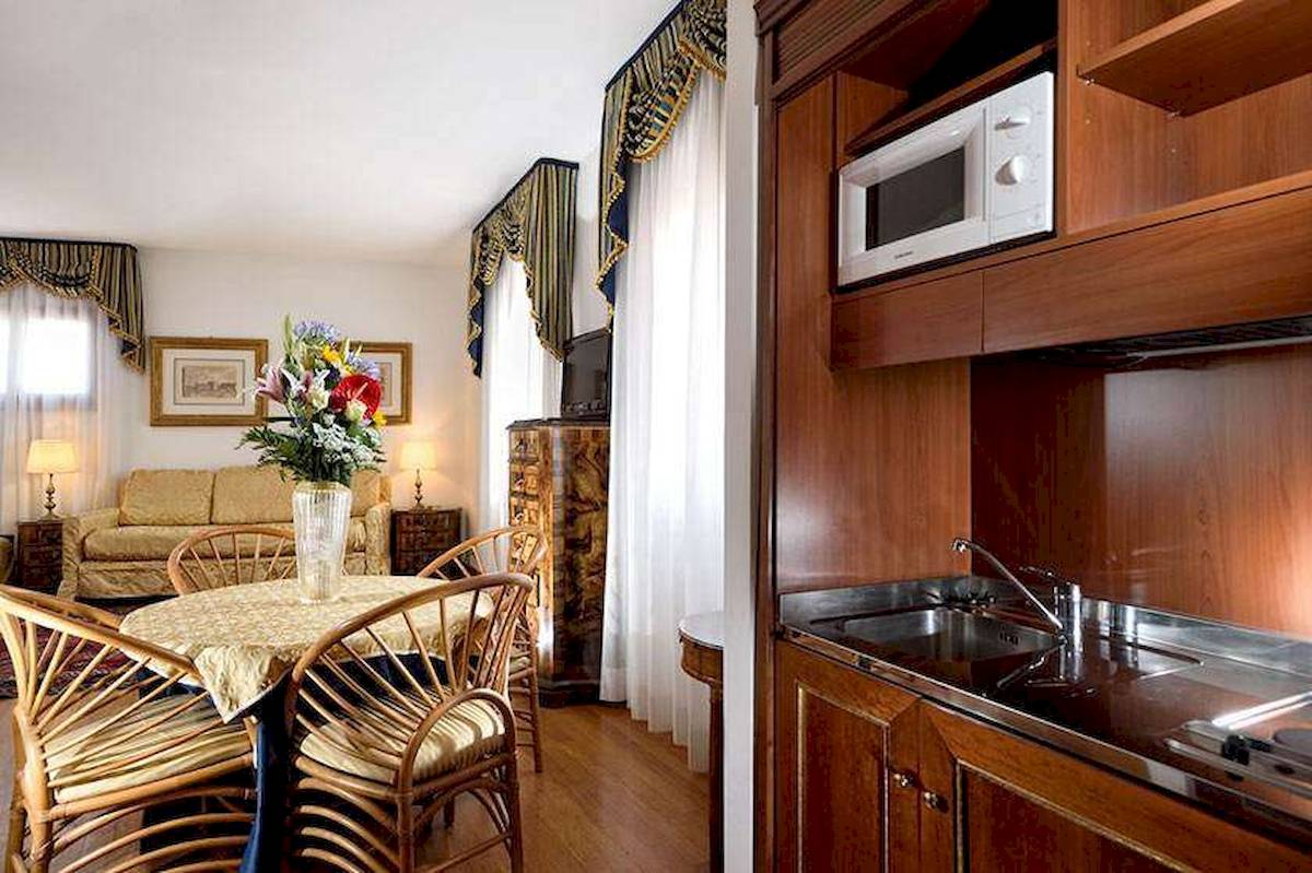 Innenansicht eines Zimmers im San Marco Palace Hotel mit Tisch, Stühlen, Couch und Küche