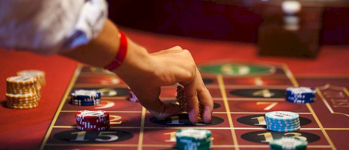 Eine Person spielt an einem Casino-Tisch mit verschiedenen Spielchips und Spielmarken.