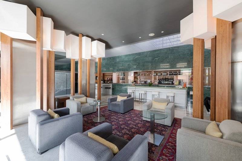 Hotellobby-Lounge-Bereich des Atenea Barcelona Aparthotel mit Sofas und einer Bar.