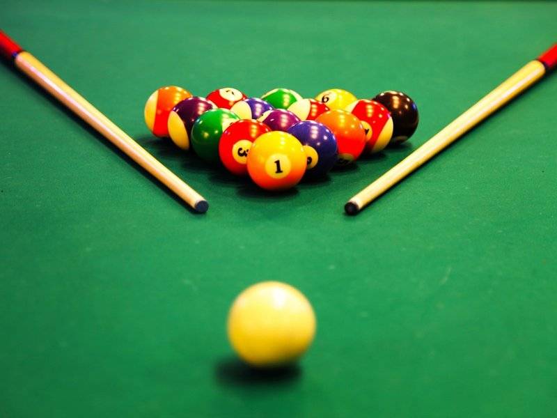 Ein Pooltisch mit bunten Kugeln und Stöcken, die Kugel Nummer 1 ist hervorgehoben.
