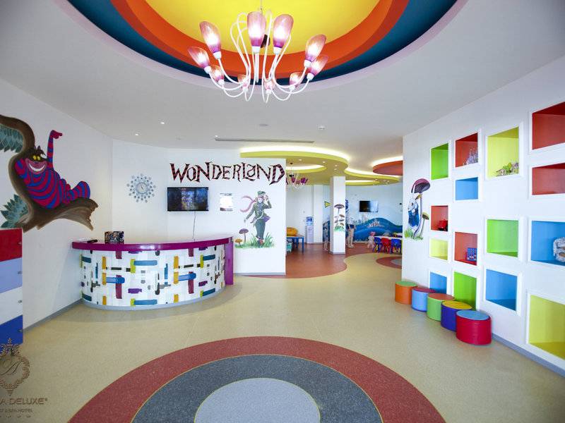 Kinderbereich im Azura Deluxe Resort & Spa mit bunten Wandmalereien, einem Empfangstresen und einer Regenbogendecke.