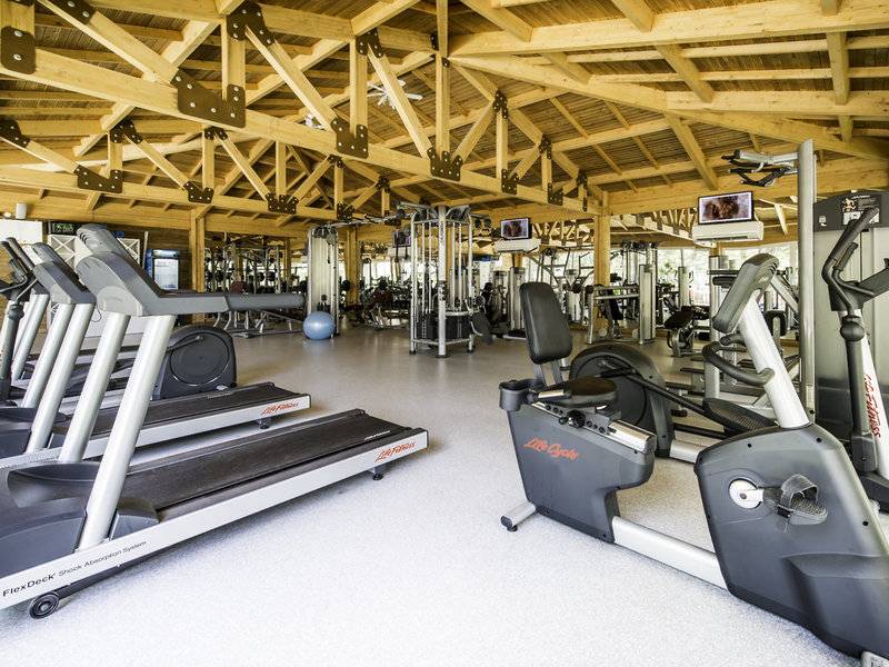Fitnessstudio im Rubi Platinum Spa Resort & Suites mit Holzdecke, Laufbändern und Fitnessgeräten.