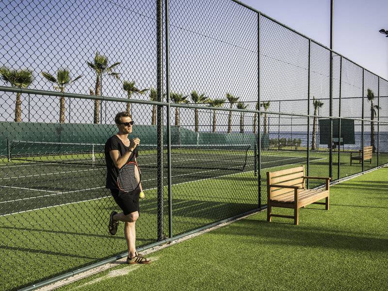 Ein Mann mit Tennisschläger und Ball steht an einem Tennisplatz im Rubi Platinum Spa Resort.