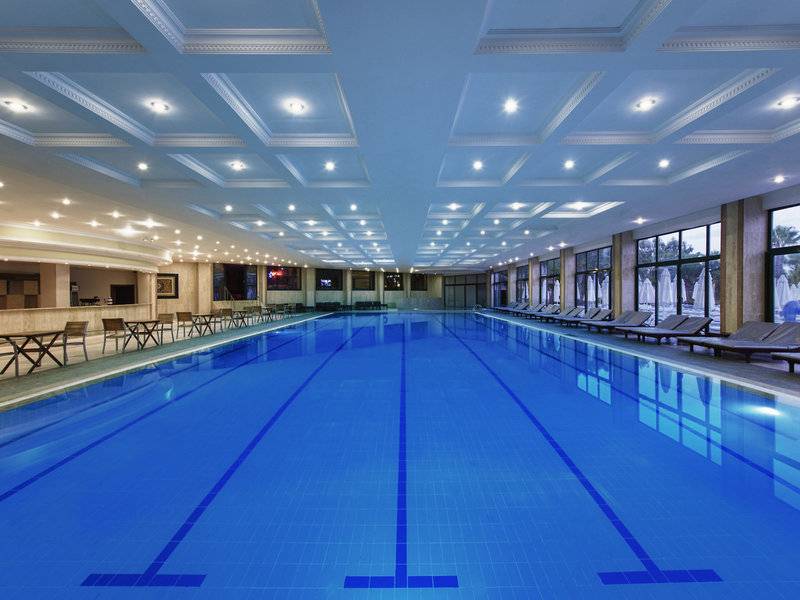 Innenpool des Delphin Deluxe Hotels mit Loungebereich und Sonnenliegen