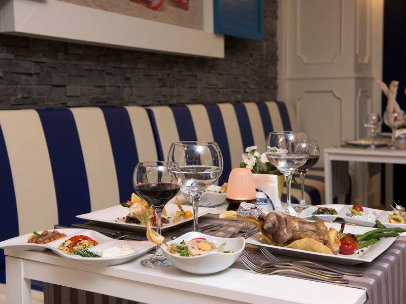 Restauranttisch im Delphin Deluxe Hotel mit Gerichten, Gläsern und Zubehör.