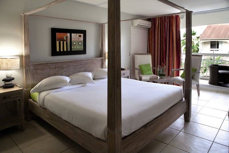 Schlafzimmer im La Pagerie - Tropical Garden Hotel mit einem Himmelbett, Kissen und einer Lampe