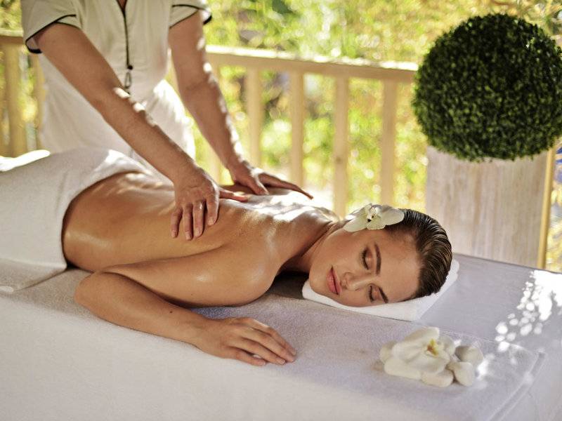Eine Frau genießt eine Massage auf einer Liege im Delphin Deluxe Hotel.