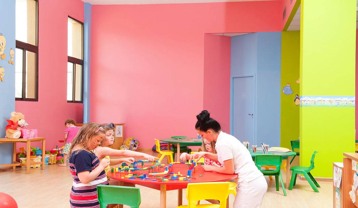 Kinder spielen in einem farbenfrohen Spielzimmer im Constantinou Bros Athena Beach Hotel.