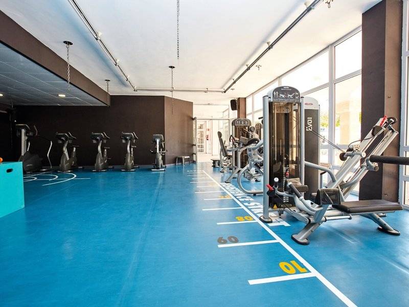 Fitnessraum im Beach Club Font de Sa Cala mit blauem Boden und verschiedenen Trainingsgeräten.