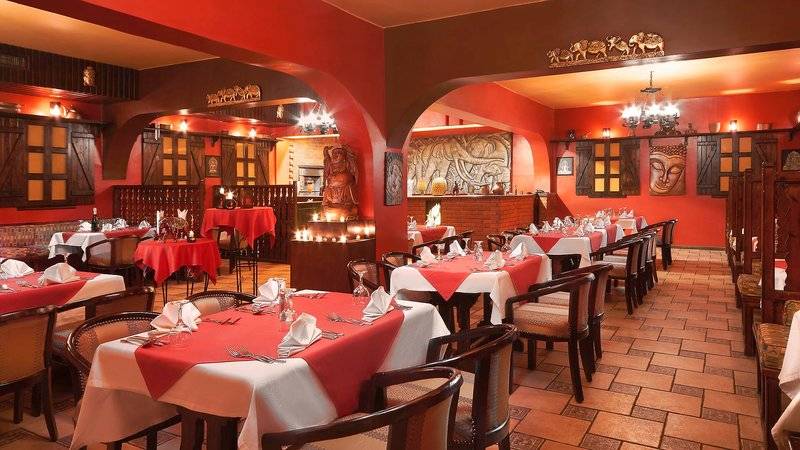 Innenansicht des Restaurants im Arabia Azur Resort mit roten Wänden und gedeckten Tischen.