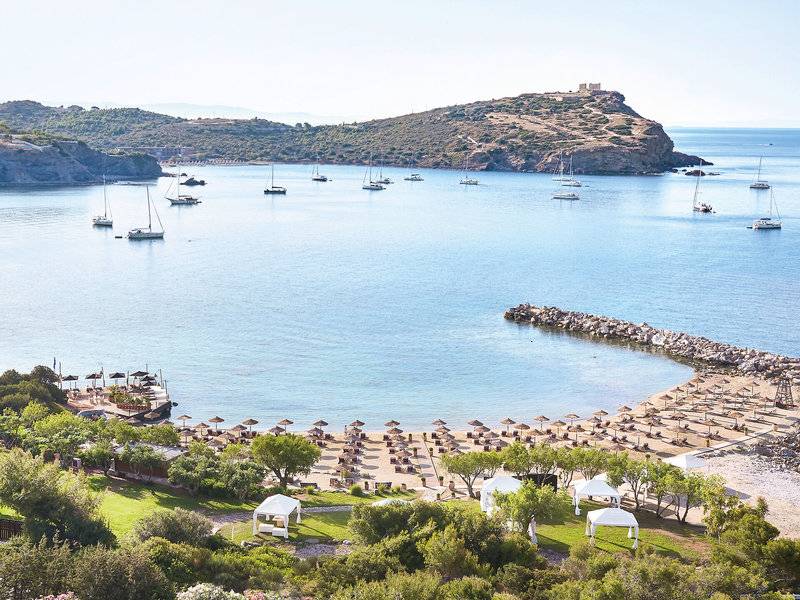 Aussicht auf das Cape Sounio Grecotel Resort mit vielen Booten im Wasser und Sonnenschirmen am Strand.