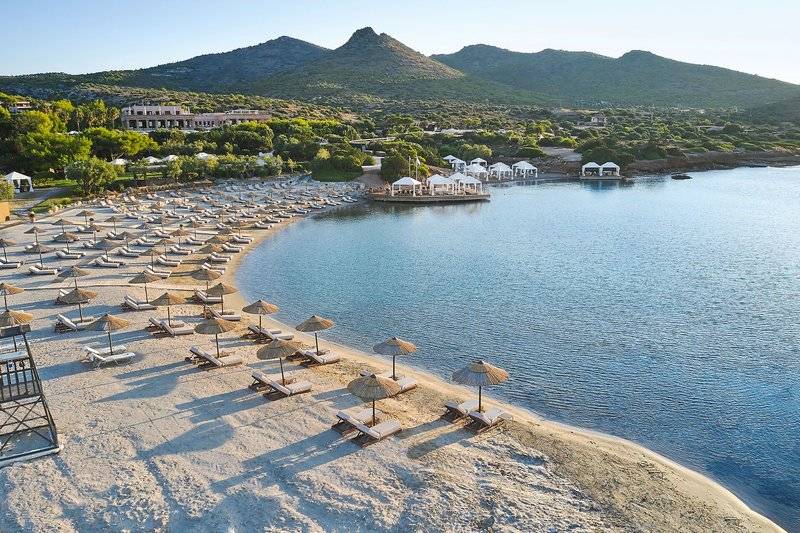 Luftaufnahme des Cape Sounio Grecotel Resorts Strand mit vielen Liegestühlen und Sonnenschirmen.