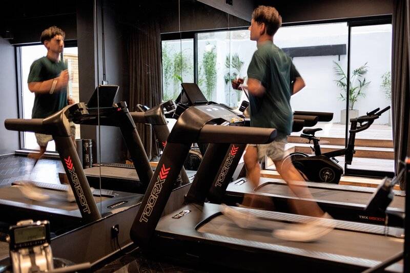 Zwei Männer laufen auf Laufbändern im Fitnessstudio des Skylark, Aluma Hotel & Resort.