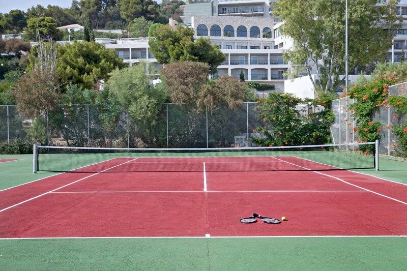 Tennisplatz vor dem Hotel Dolce Athens Attica Riviera mit Tennisschlägern und Ball