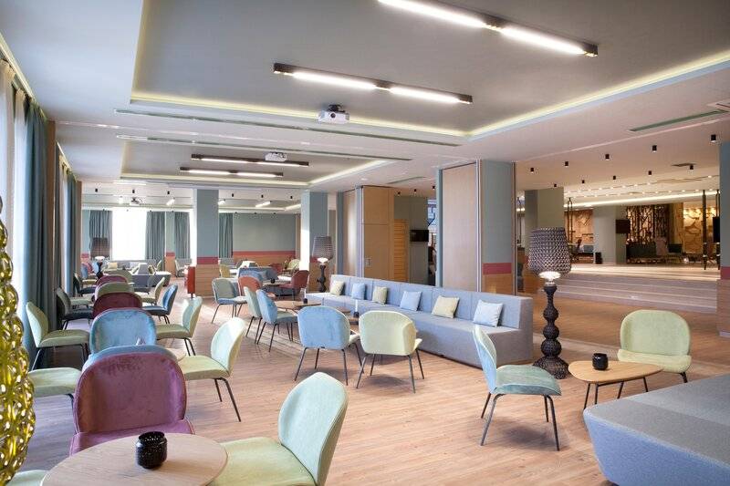 Hotellobby des Dolce Athens Attica Riviera mit bunten Stühlen, Tischen und Sofas.