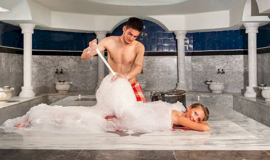 Mann und Frau spielen mit Seifenblasen im Badezimmer des Sultan of Dreams Hotels.