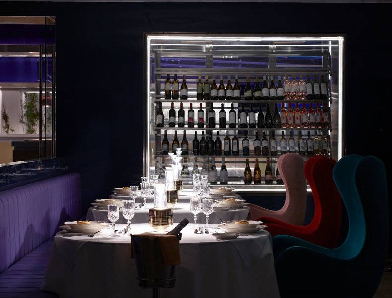 Innenansicht des Restaurants im I Resort Beach Hotel & Spa mit Tisch und gefülltem Weinregal.