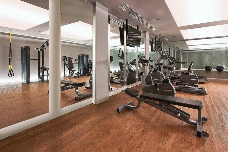 Fitnessstudio im Neme Design Hotel mit diversen Trainingsgeräten und Spiegeln.