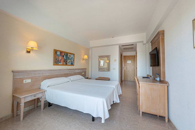 Doppelbettzimmer im La Santa Maria Playa Hotel mit Fernseher, Schreibtisch und Nachttischen.