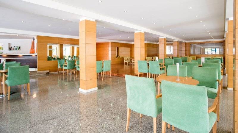 Innenbereich des Restaurants im La Santa Maria Playa Hotel mit grünen Stühlen und Holztischen.