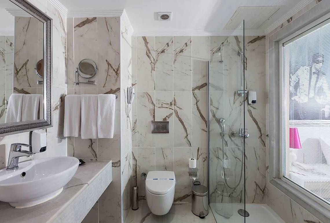 Badezimmer des Sultan of Dreams Hotels mit Marmorwänden, Dusche, Toilette, Waschbecken und Spiegeln.