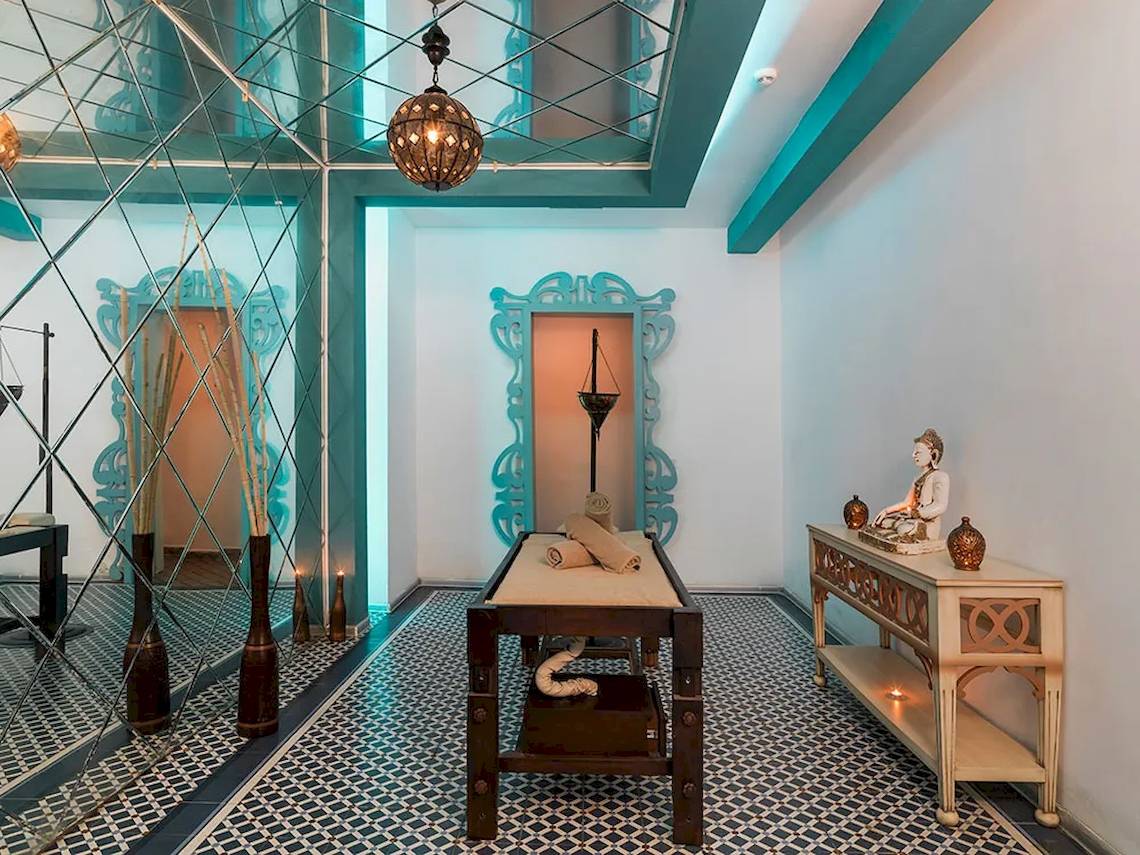 Behandlungsraum im Sultan of Dreams Hotel Spa mit Liege, Tisch, Buddha-Statue und blauen Wandverkleidungen.