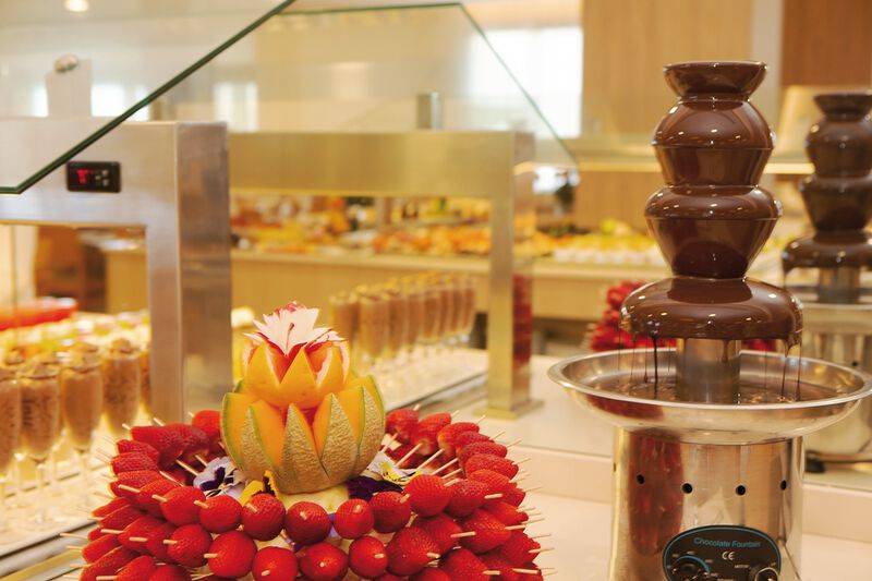 Schokoladenfontaine im Buffet des Sabina Playa Hotels mit Früchten und Getränken im Hintergrund.