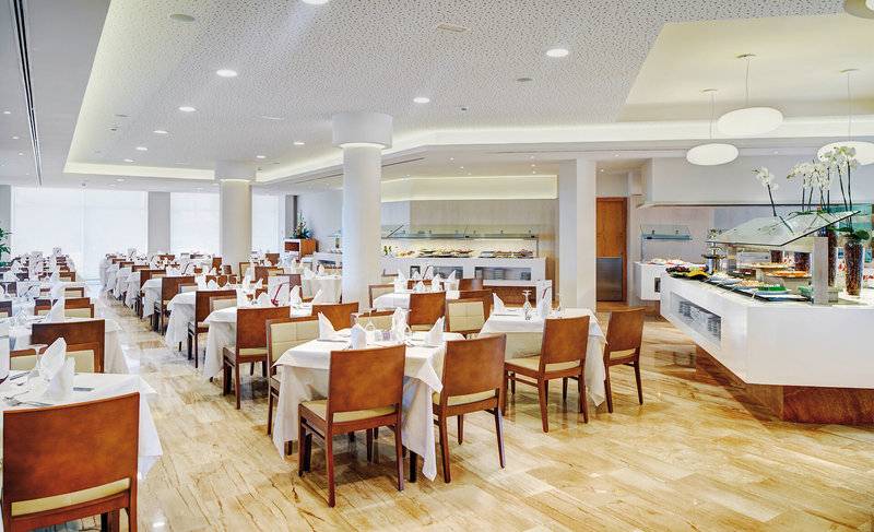 Restaurant im Hipotels Dunas Cala Millor mit gedeckten Tischen und Buffet.
