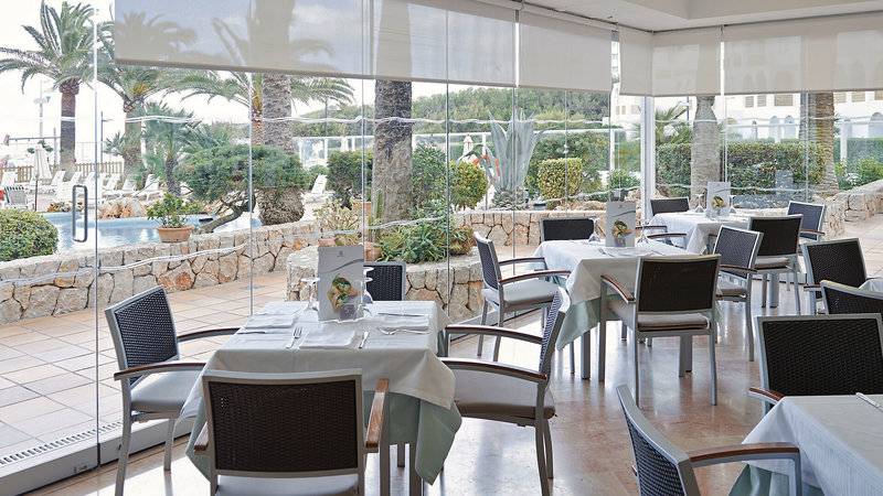 Restaurant im Hipotels Dunas Cala Millor mit großen Glaswänden und Blick auf den Pool.