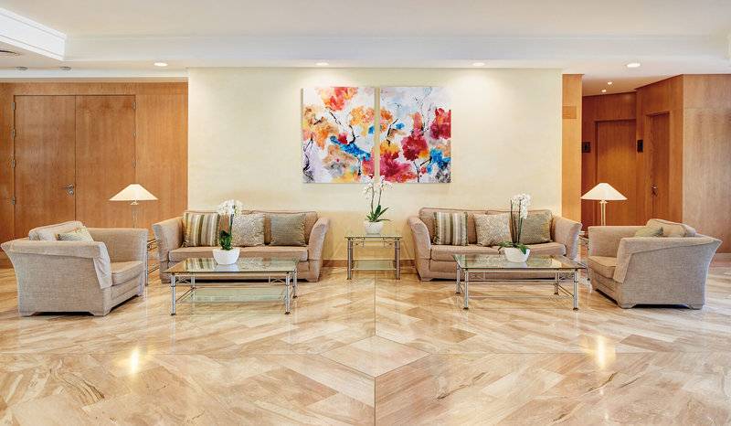 Hotellobby von Hipotels Dunas Cala Millor mit Sofas, Tischen und Gemälden.