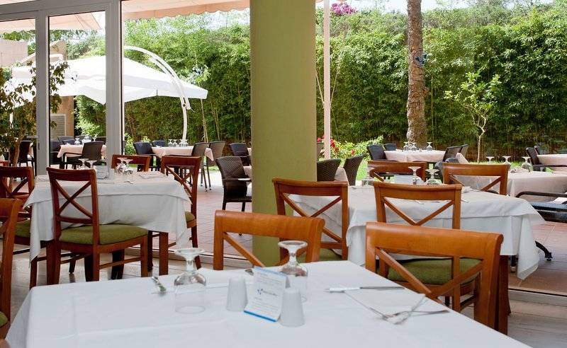 Gartenrestaurant im Bakour Garbi Cala Millor Hotel mit Tischen und Stühlen unter weißen Sonnenschirmen.