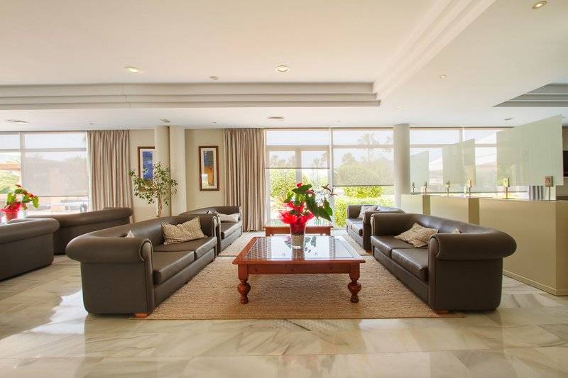 Loungebereich des Bakour Garbi Cala Millor Hotels mit mehreren Sofas, einem Tisch und Pflanzen.