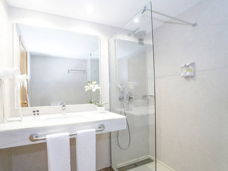 Ein Badezimmer mit einer Glasdusche, einem Spiegel und einem Waschbecken mit Handtüchern.
