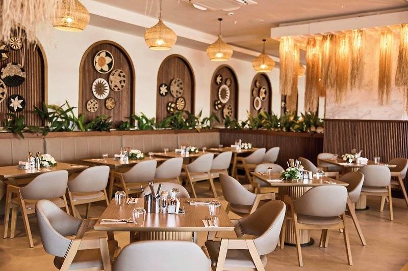 Innenansicht des Restaurants im Aldiana Club Side Beach mit vielen Tischen und Stühlen, Holzdesign und dekorativen Wandelementen.