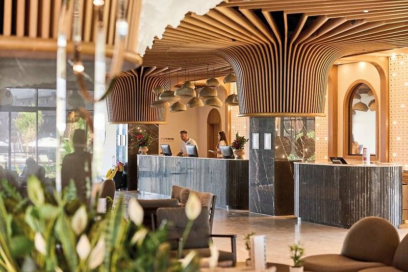 Rezeption des Aldiana Club Side Beach Hotels mit Marmorrezeptionstheke und Holzdecke.