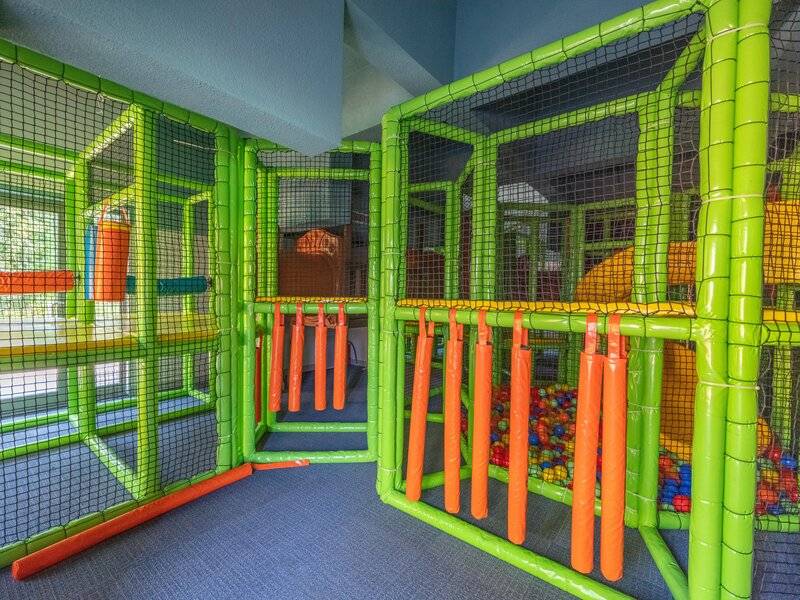 Kinderspielplatz im Sherwood Exclusive Kemer Hotel mit grünen und orangefarbenen Strukturen und Netzen.