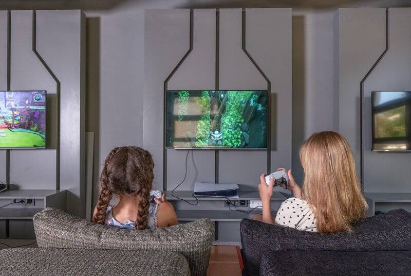 Zwei Kinder spielen Videospiele im Sherwood Exclusive Kemer Hotel.